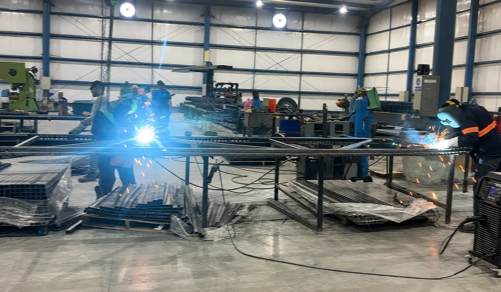 Dos soldadores de SMACERO trabajando sobre estructuras metálicas en planta